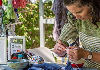 Woman crafting outside her booth
